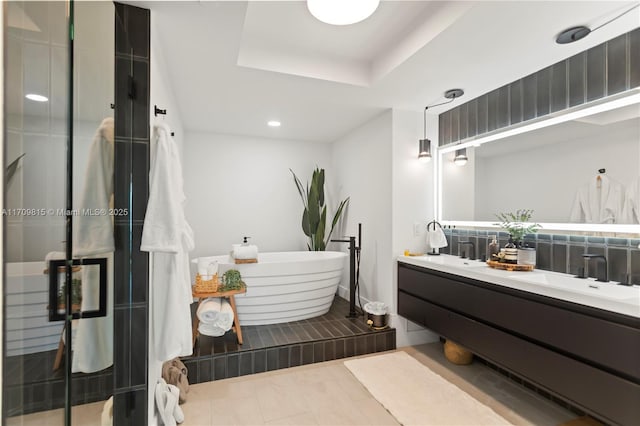 bathroom featuring a tray ceiling, vanity, and independent shower and bath