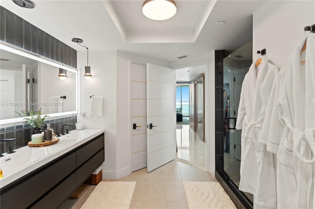 bathroom featuring tile patterned floors, vanity, a raised ceiling, and a shower with shower door