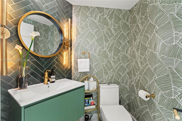 bathroom featuring vanity, toilet, and tile walls