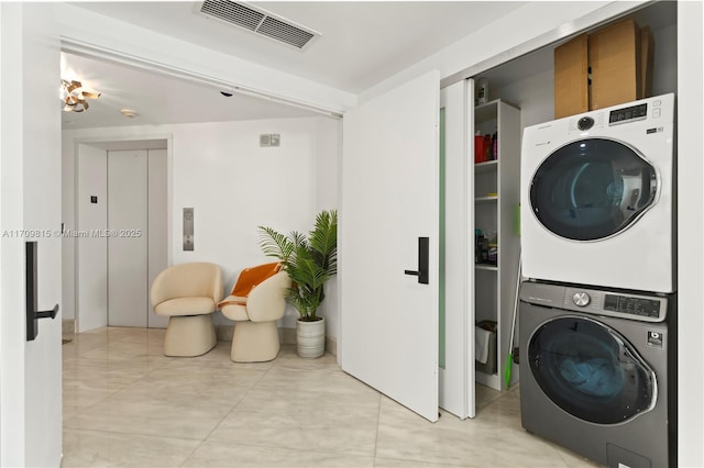 laundry room with elevator, cabinets, and stacked washer / drying machine