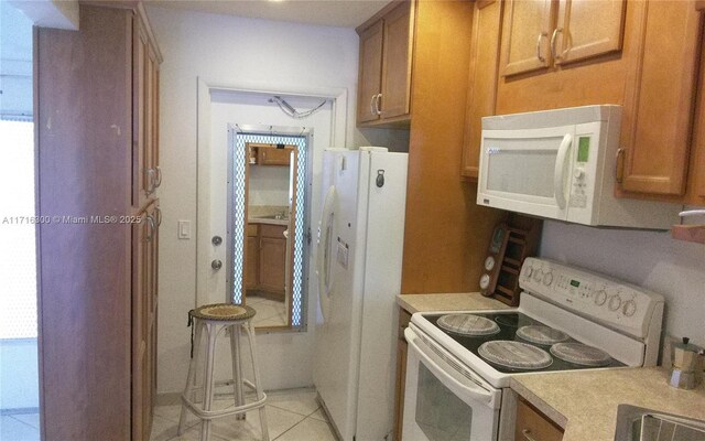 kitchen with light tile patterned floors, white appliances, and a wealth of natural light