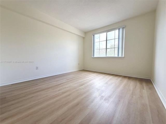 spare room featuring light hardwood / wood-style floors and a textured ceiling