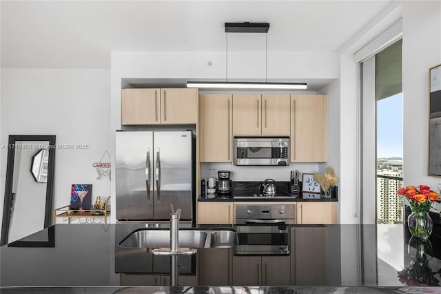 kitchen with dark countertops, light brown cabinets, stainless steel appliances, and a sink