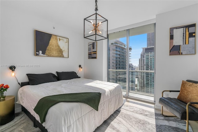 bedroom featuring a view of city, a chandelier, and floor to ceiling windows