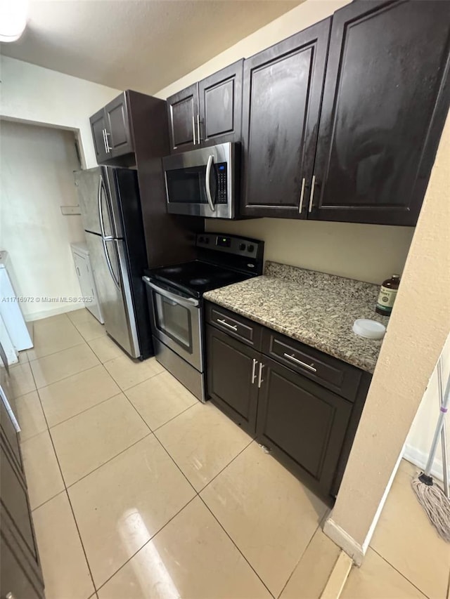 kitchen featuring light stone countertops, appliances with stainless steel finishes, and light tile patterned flooring