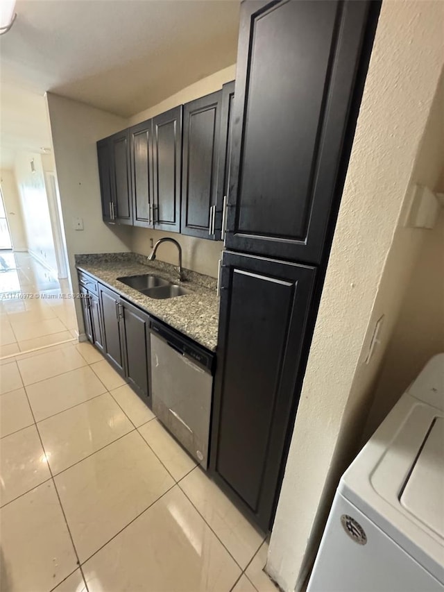 kitchen with stone counters, dishwasher, sink, washer / clothes dryer, and light tile patterned flooring