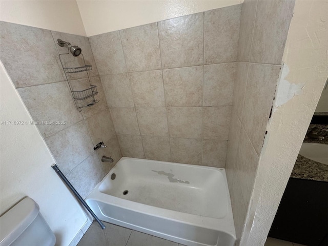 bathroom featuring tile patterned flooring, toilet, and tiled shower / bath