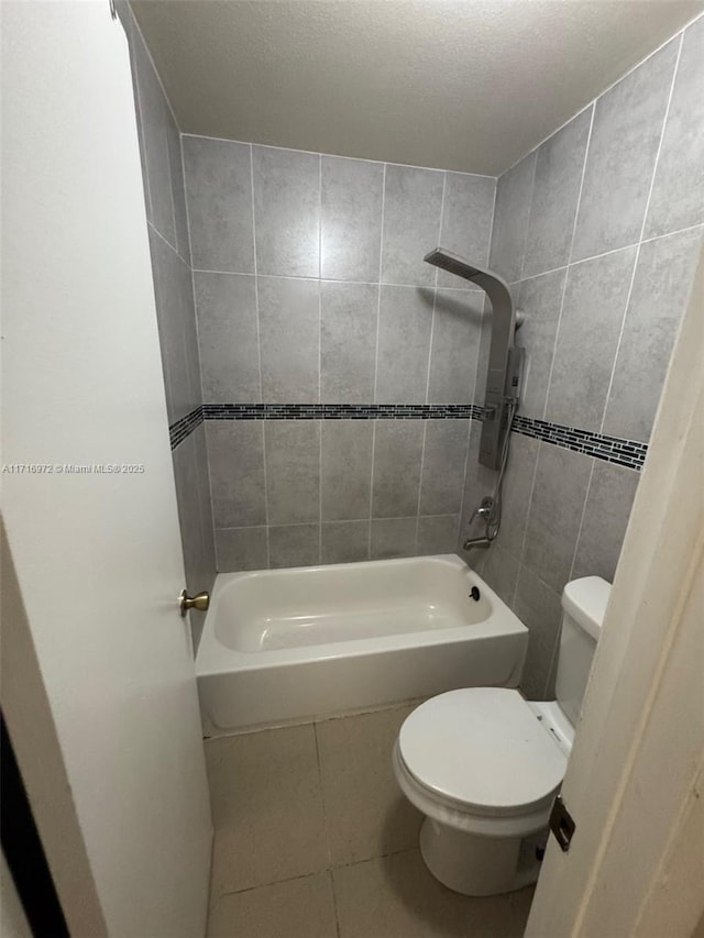 bathroom with tile patterned flooring, toilet, washtub / shower combination, and tile walls