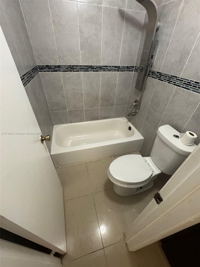 bathroom with tile patterned flooring, toilet, tile walls, and tub / shower combination