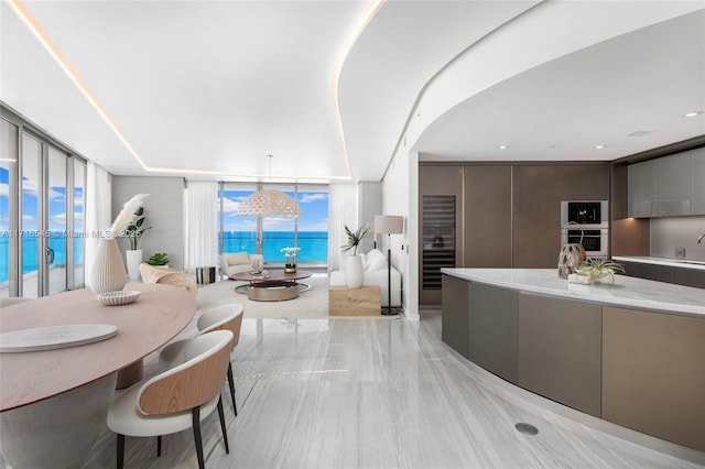 interior space featuring floor to ceiling windows, stainless steel oven, a water view, and pendant lighting