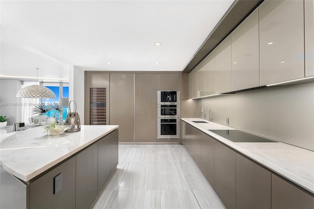 kitchen featuring built in microwave, sink, hanging light fixtures, gray cabinets, and black electric stovetop