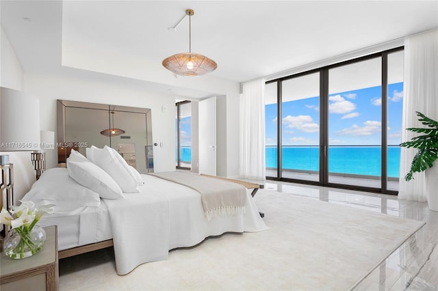 bedroom with access to outside, a water view, and a wall of windows