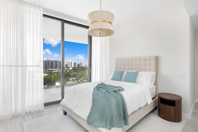 bedroom with access to exterior, light hardwood / wood-style flooring, and expansive windows