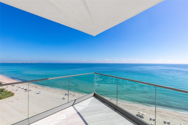 balcony with a water view and a view of the beach