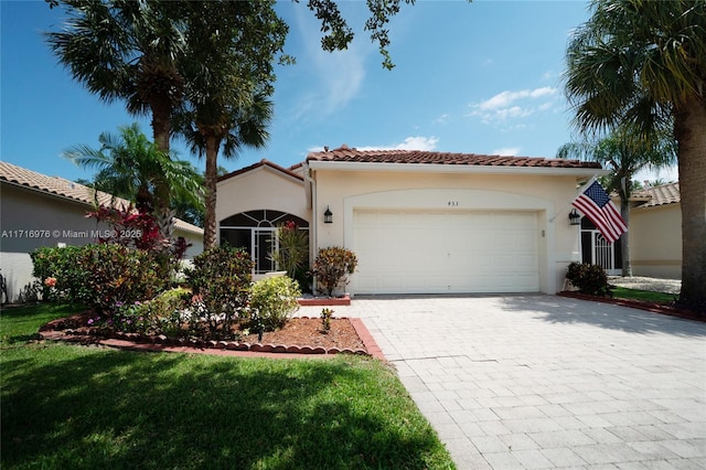 mediterranean / spanish-style house with stucco siding, a tile roof, decorative driveway, and a garage