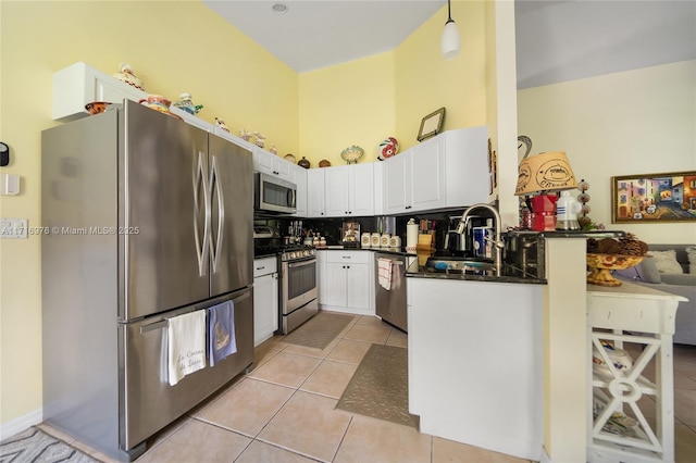 kitchen with dark countertops, light tile patterned floors, appliances with stainless steel finishes, white cabinetry, and a sink