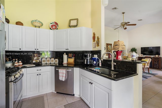 kitchen featuring a sink, stainless steel appliances, a peninsula, white cabinets, and light tile patterned floors