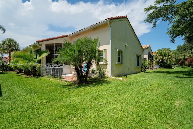 back of property featuring stucco siding, a lawn, and a tile roof