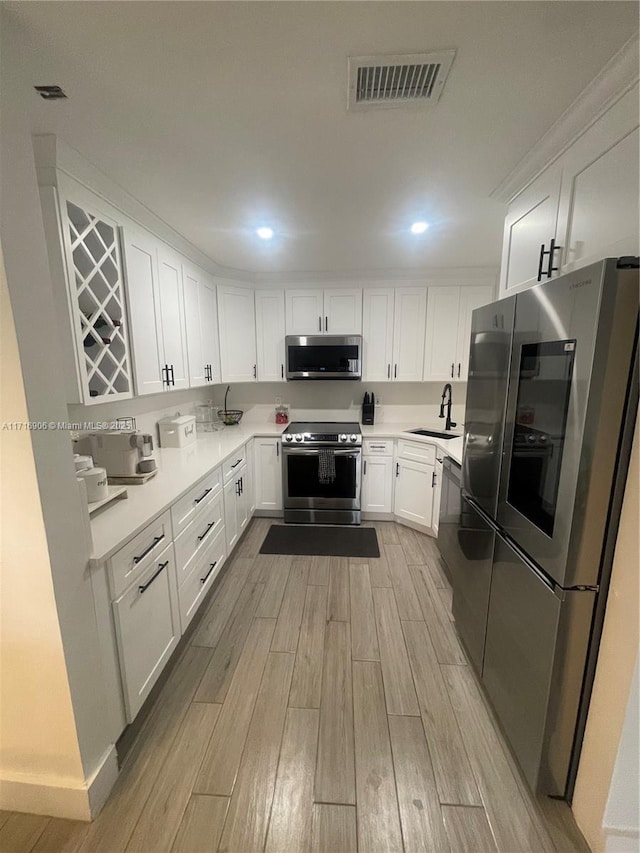 kitchen featuring white cabinets, sink, light wood-type flooring, and stainless steel appliances