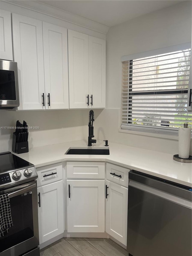 kitchen featuring white cabinets, sink, stainless steel appliances, and light hardwood / wood-style flooring