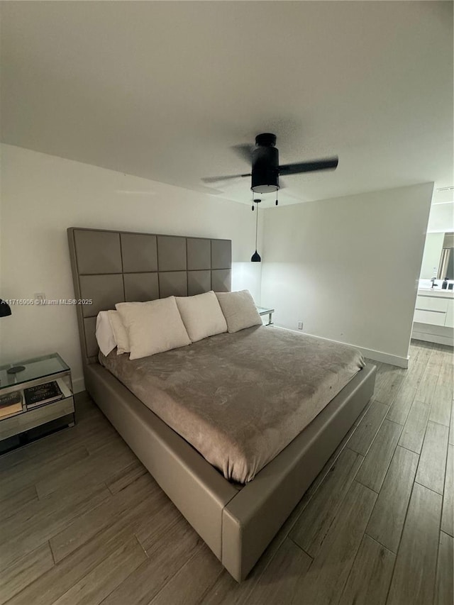 bedroom featuring light wood-type flooring, ceiling fan, and connected bathroom