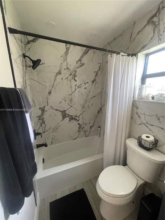 bathroom featuring shower / bath combination with curtain, toilet, and tile walls