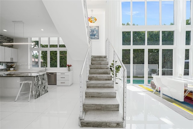 stairway featuring tile patterned floors, sink, a high ceiling, and plenty of natural light