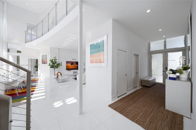 foyer entrance with tile patterned floors, french doors, and a towering ceiling