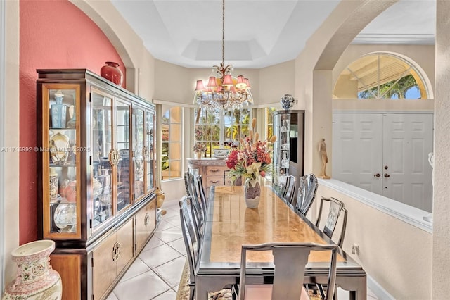 dining space featuring a tray ceiling, light tile patterned floors, a high ceiling, and an inviting chandelier