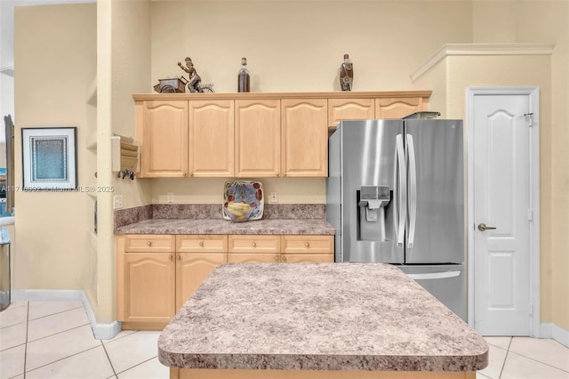 kitchen featuring stainless steel fridge, light brown cabinets, light tile patterned floors, and a kitchen island