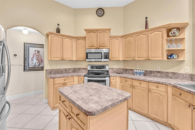 kitchen featuring appliances with stainless steel finishes, sink, light brown cabinets, light tile patterned floors, and a kitchen island