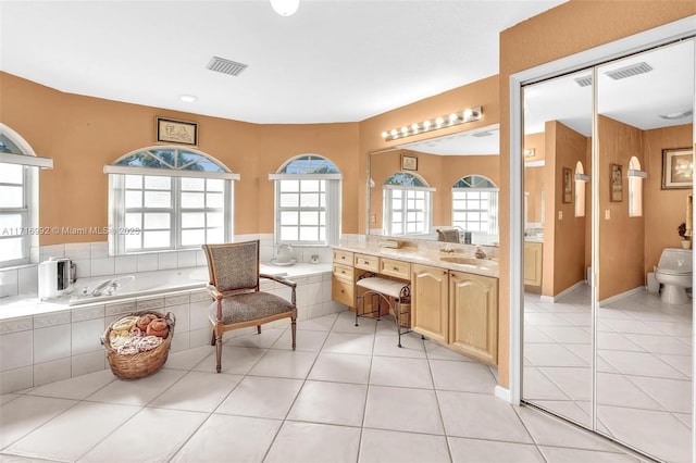 bathroom featuring tile patterned flooring, vanity, and tiled bath