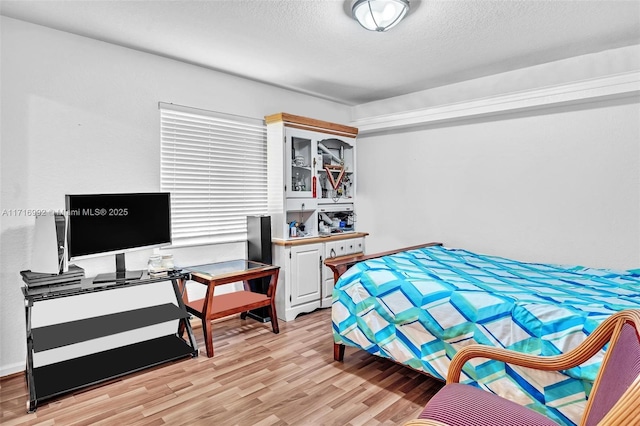 bedroom with light hardwood / wood-style flooring and a textured ceiling