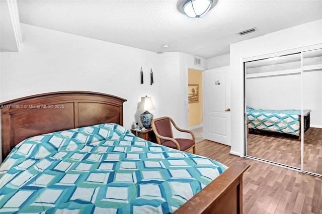 bedroom with wood-type flooring, a textured ceiling, and a closet