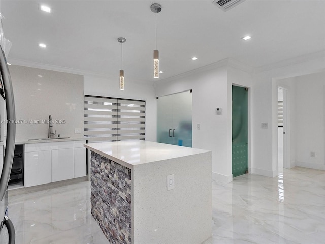 kitchen featuring ornamental molding, sink, decorative light fixtures, white cabinets, and a center island