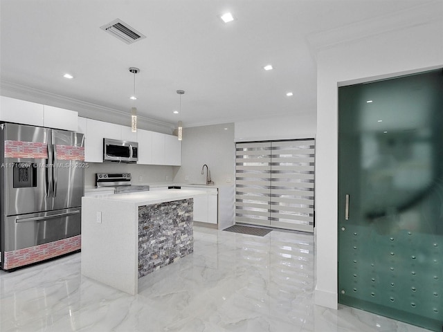 kitchen featuring pendant lighting, a center island, white cabinets, crown molding, and appliances with stainless steel finishes