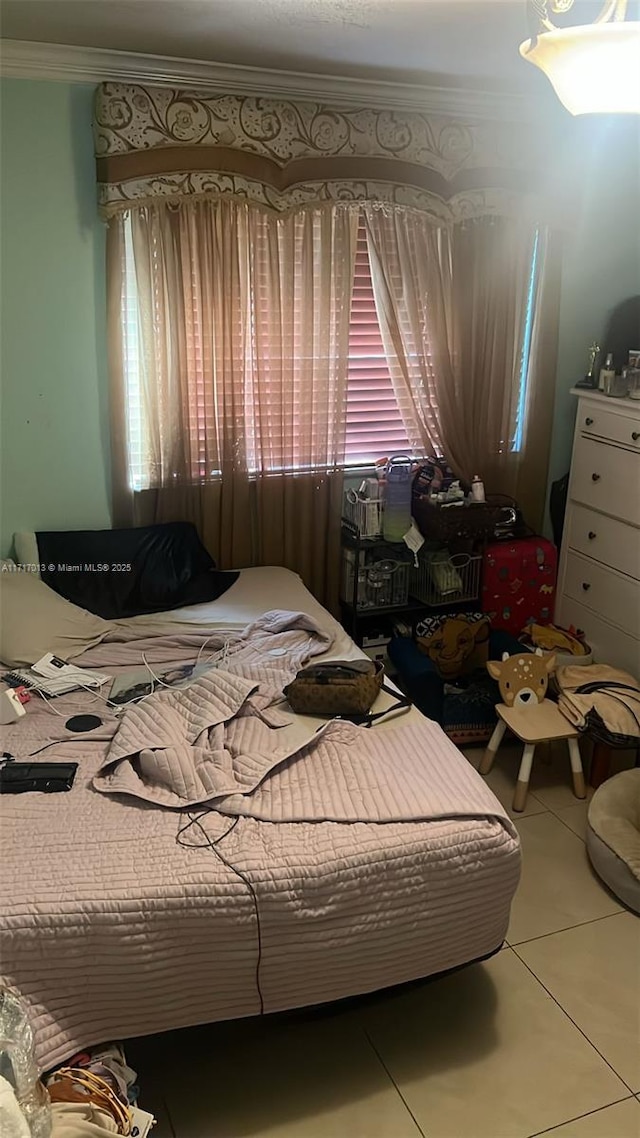 bedroom with tile patterned floors, multiple windows, and ornamental molding