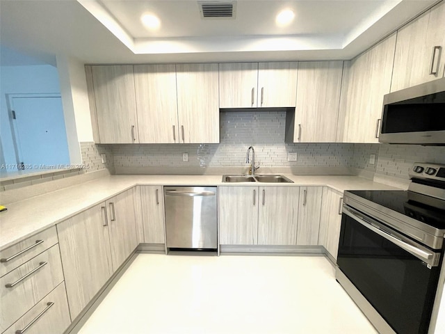 kitchen with backsplash, light brown cabinetry, sink, and appliances with stainless steel finishes