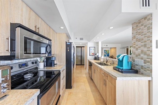 kitchen featuring sink, stainless steel appliances, light stone counters, decorative backsplash, and light tile patterned floors