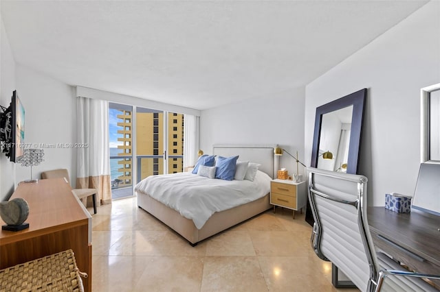 bedroom featuring a water view and a wall of windows