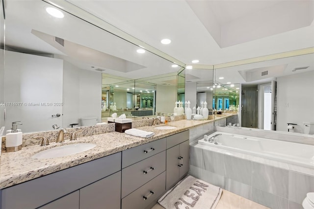 bathroom with vanity, toilet, and tiled tub