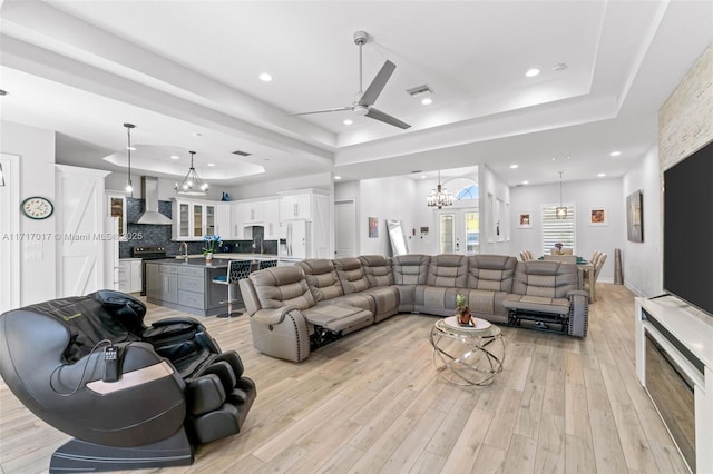 living room featuring ceiling fan, a raised ceiling, light wood-type flooring, and sink