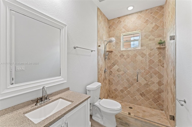 bathroom with vanity, toilet, and a shower with door