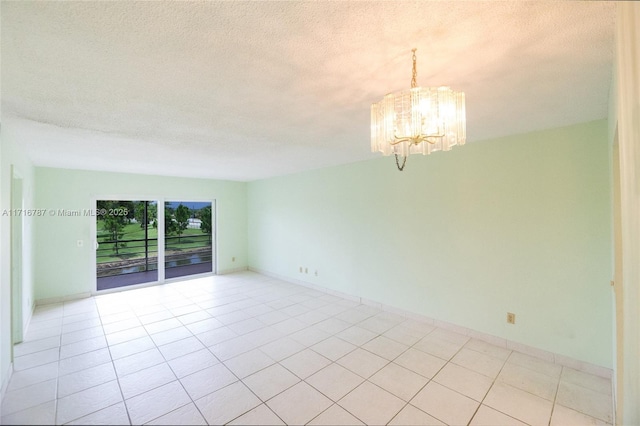 tiled empty room with a textured ceiling and a chandelier