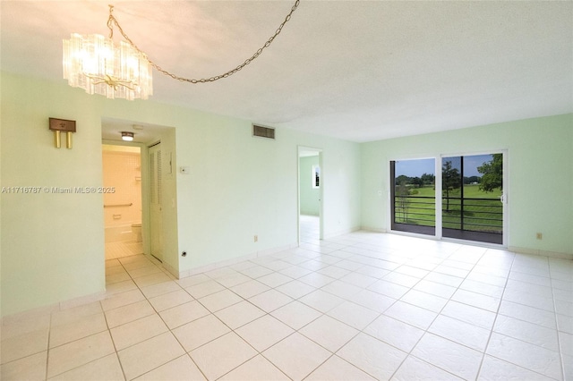 unfurnished room with light tile patterned flooring and an inviting chandelier