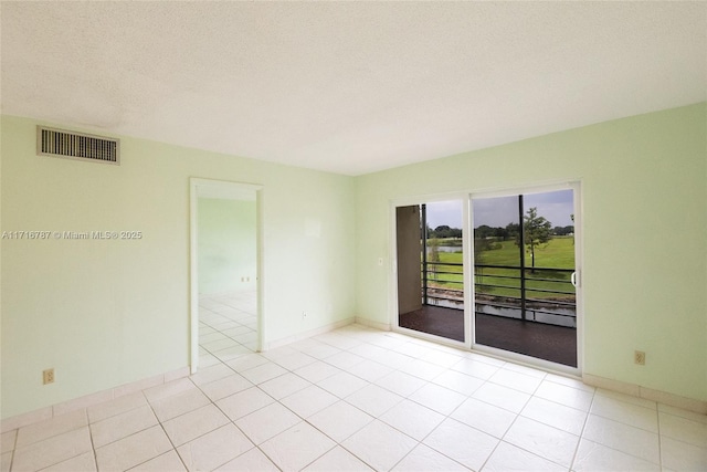 spare room featuring light tile patterned floors and a textured ceiling