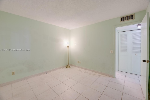 tiled spare room featuring a textured ceiling