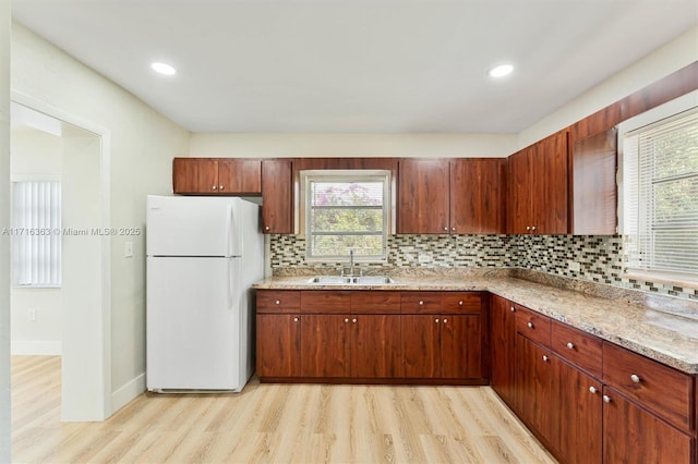 kitchen with white fridge, a healthy amount of sunlight, sink, and light hardwood / wood-style flooring