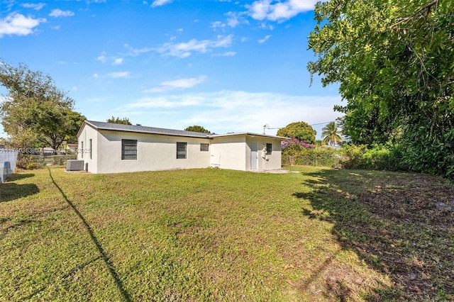 rear view of property with a lawn and central air condition unit