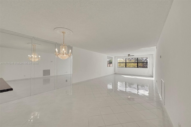 tiled empty room with a textured ceiling and ceiling fan with notable chandelier